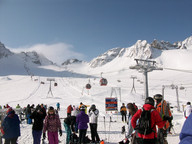 Narciarze na tle trasy i gondolek