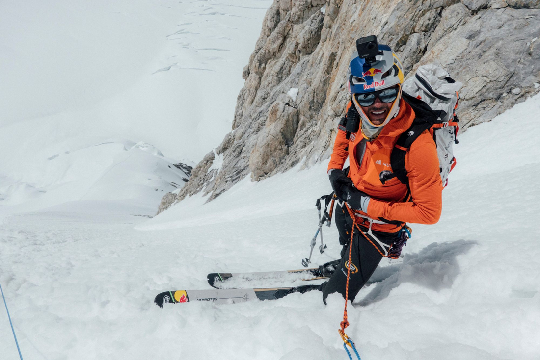 Andrzej Bargiel zjeżdża na nartach po stromym stoku himalajskim ndrzej Bargiel w kasku Red Bull zjeżdża na nartach Salomon po stromym, śnieżnym stoku himalajskim z uśmiechem na twarzy