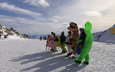 Narciarze przebrani za różne zwierżeta, w tym za dinozaury na ośnieżonym stoku w Zillertal