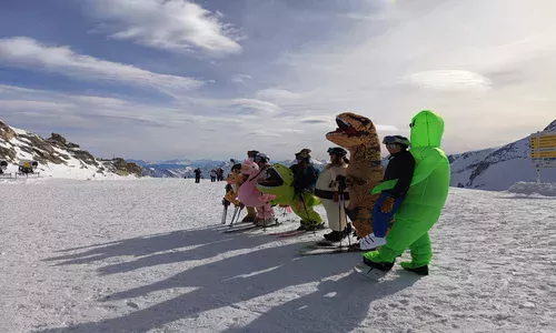 Narciarze przebrani za różne zwierżeta, w tym za dinozaury na ośnieżonym stoku w Zillertal