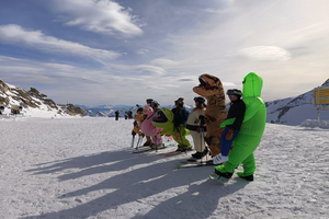 Narciarze przebrani za różne zwierżeta, w tym za dinozaury na ośnieżonym stoku w Zillertal