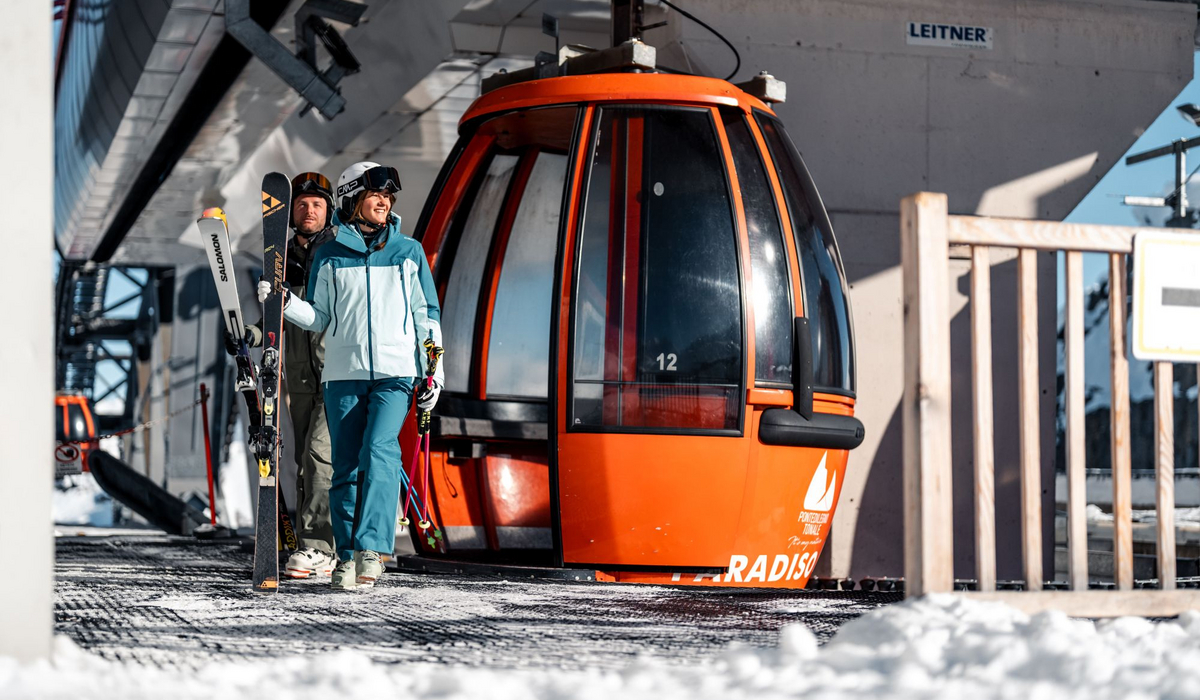Czerwona, okrągła gondolka na górnej stacji w paso Tonale, osoby z miej wysiadają