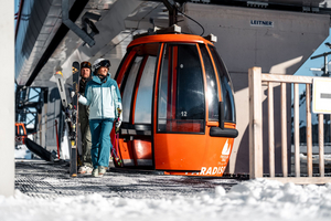 Czerwona, okrągła gondolka na górnej stacji w paso Tonale, osoby z miej wysiadają