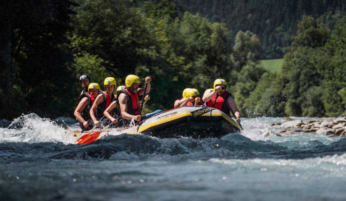W rytmie prawdziwej natury, czyli camping i rafting w Zillertal © Zillertal Tourismus / Christoph Johann Grupa ludzi w żółtych kaskach spływająca pontonem po rwącej rzece w górach