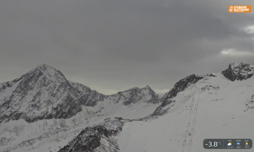 Widok z kamery internetowej - Stubai 23 10 2026 / https://www.stubai.at/pl/kamery-live/? Zaśnieżone szczyty nad lodowcem Stubai przy pochmurnym niebie