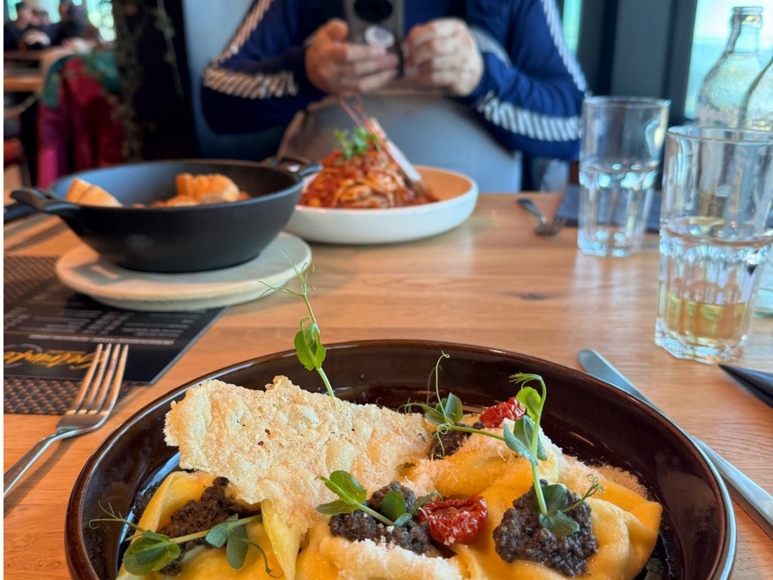 Ravioli z Grana Padano i pesto z trufli, w głebi autor filmujący swoje danie Ravioli z Grana Padano i pesto z trufli, w głebi autor filmujący swoje danie