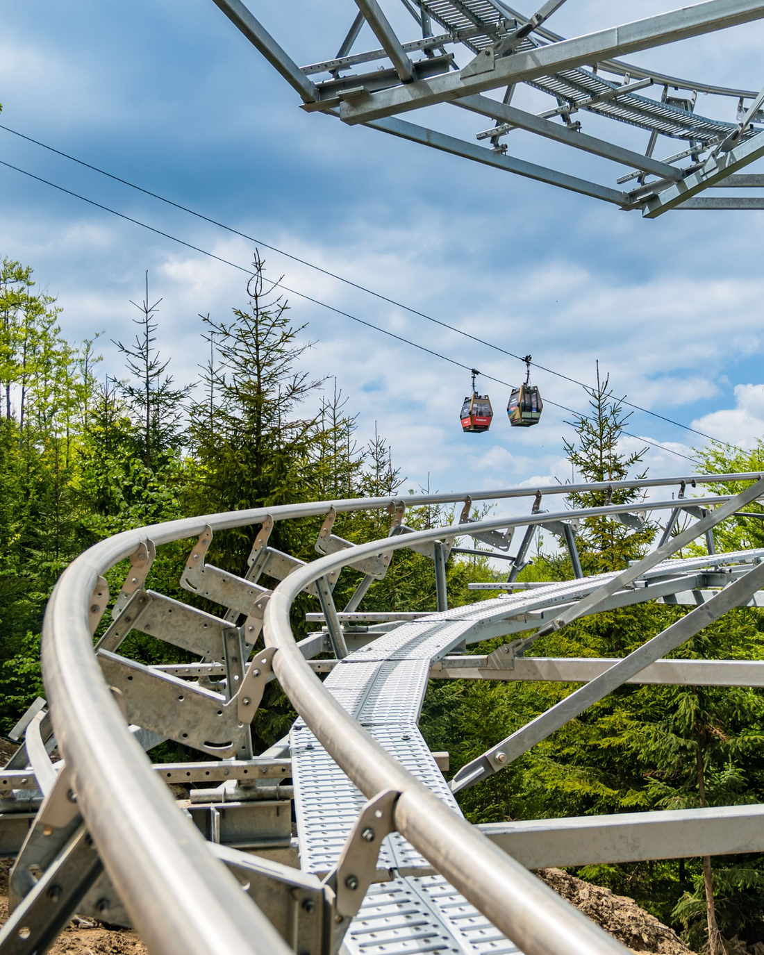 Salamandra Alpine Coaster Szczyrk – tor i wagoniki kolejki grawitacyjnej podczas budowy Tor kolejki grawitacyjnej Salamandra Alpine Coaster z widoczną gondolą wyciągu w tle, Szczyrk Mountain Resort