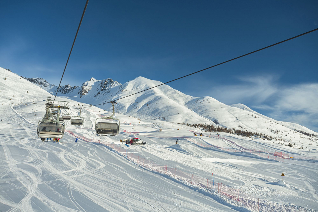 Wyciąg krzesełkowy na stoku narciarskim Passo del Tonale z widokiem na ośnieżone szczyty Alp i lodowiec Presena w słoneczny zimowy dzień