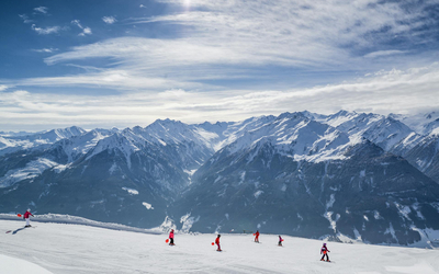 6 osób jeździ na nartach, w tle góry