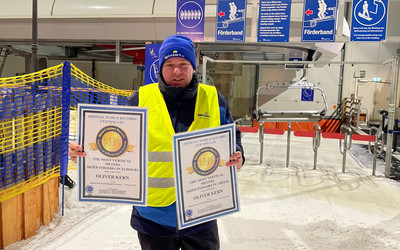 Oliver Kern na stoku w hali narciarskiej trzymajacy w rękach certyfikaty pomicia rekordów świata.