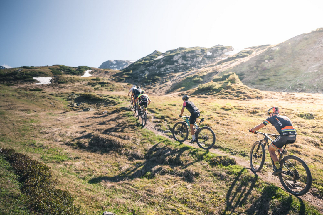 Techniczny zjazd MTB w Obertauern – enduro i trasy górskie w Ziemi Salzburskiej Trzech rowerzystów MTB na kamienistym technicznym zjeździe w Obertauern przy zachodzie słońca – trasy enduro w Alpach Salzburskich